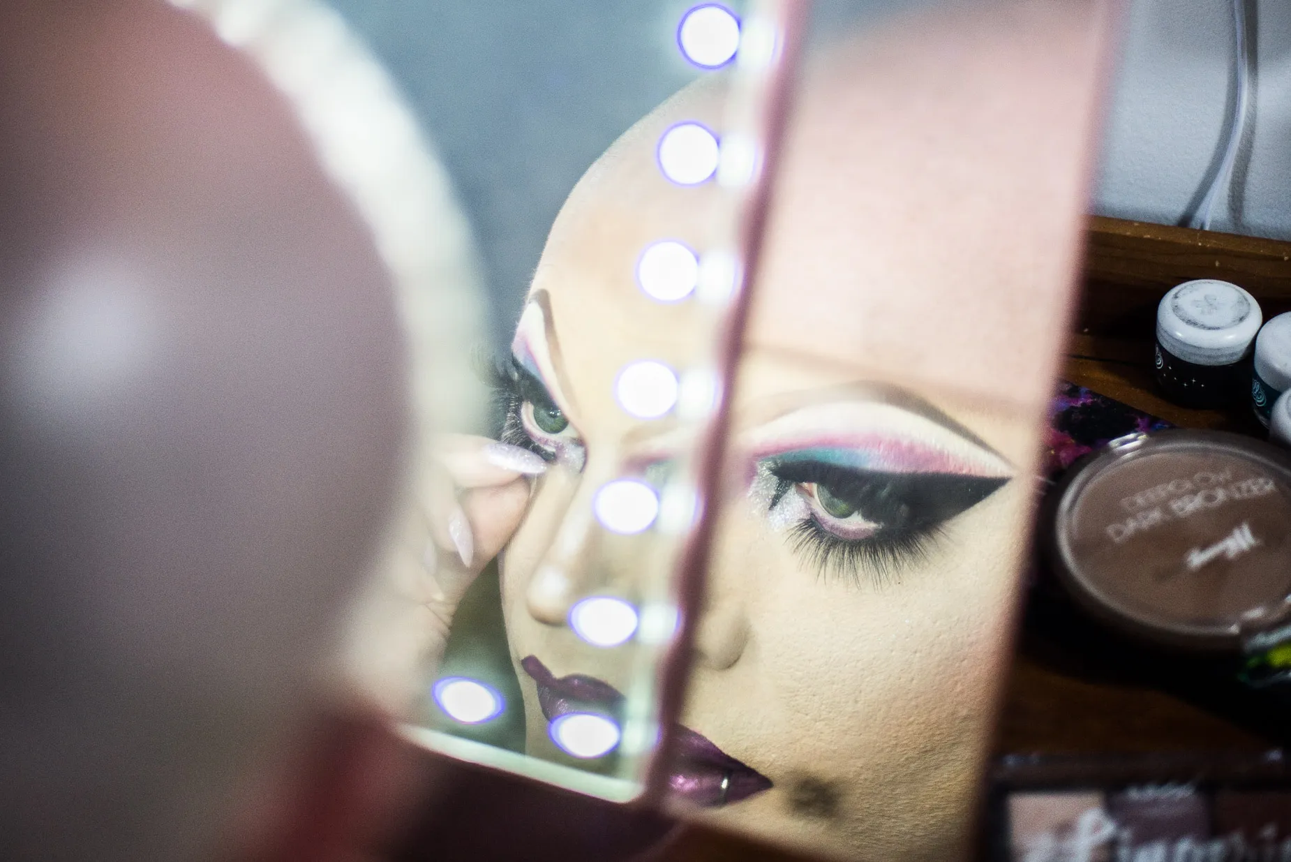 Soren doing eye make up in the mirror before drag performance. From the When I'm Here Series a Photography Project by Darran K Roper