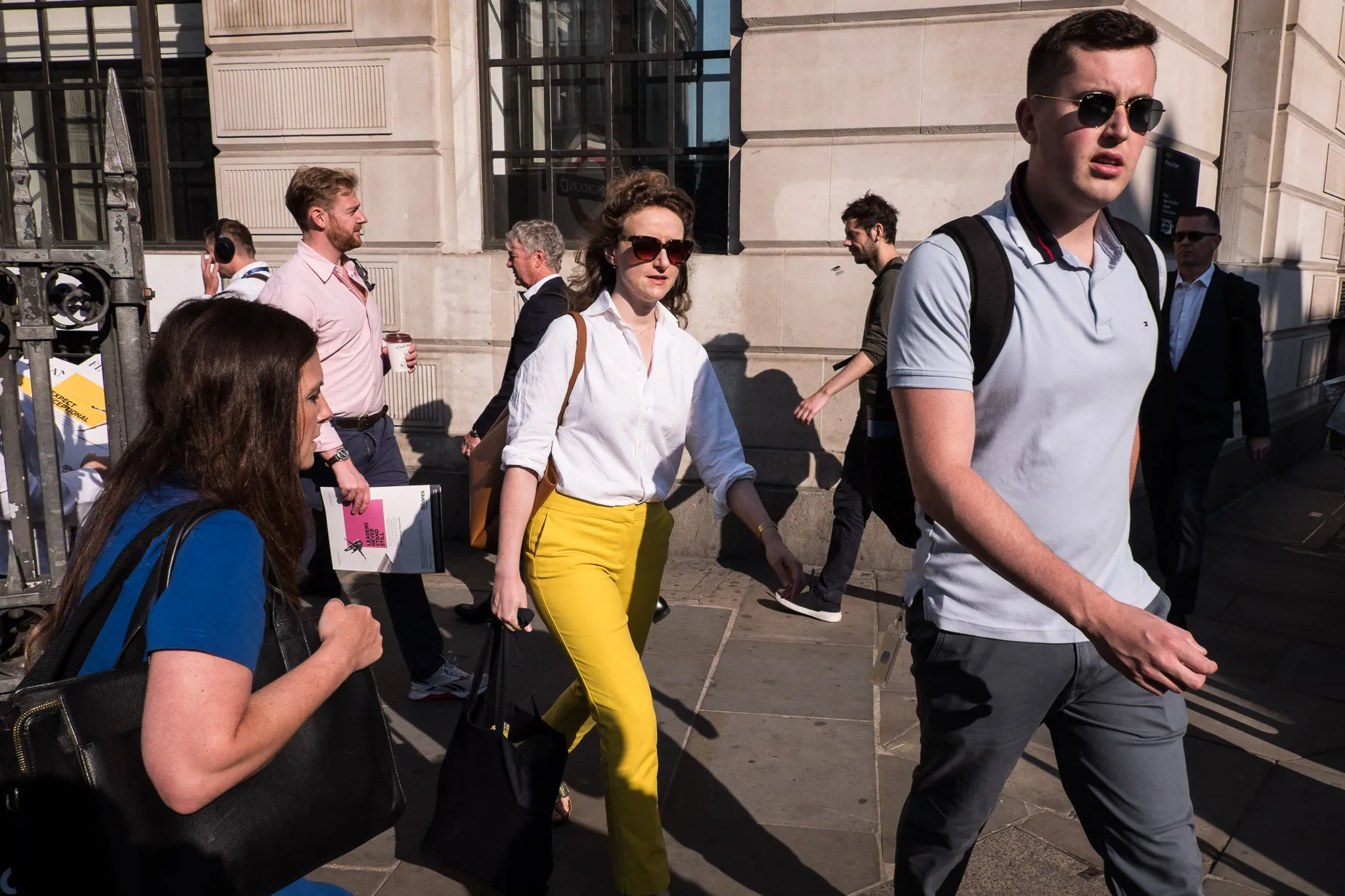 Woman in bright yellow trousers, morning commuters outside Bank station