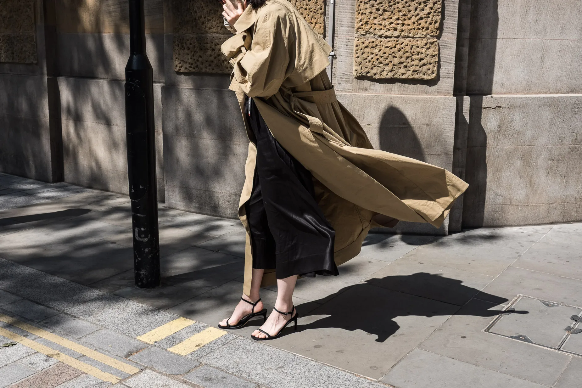 Woman wearing beige trench coat in a gust of wind