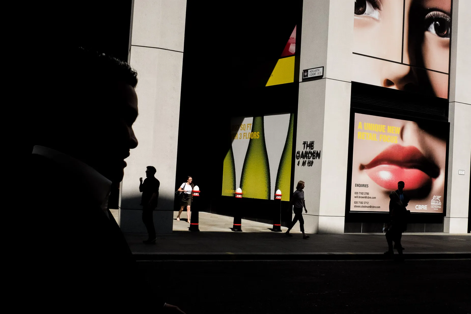 Large face on billboard with silhouettes of pedestrians on Fenchurch street
