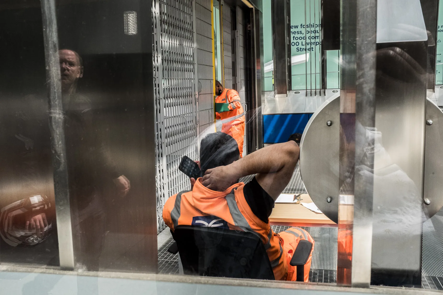 Reflection photograph Liverpool Street employees working with motorcycle rider passer by