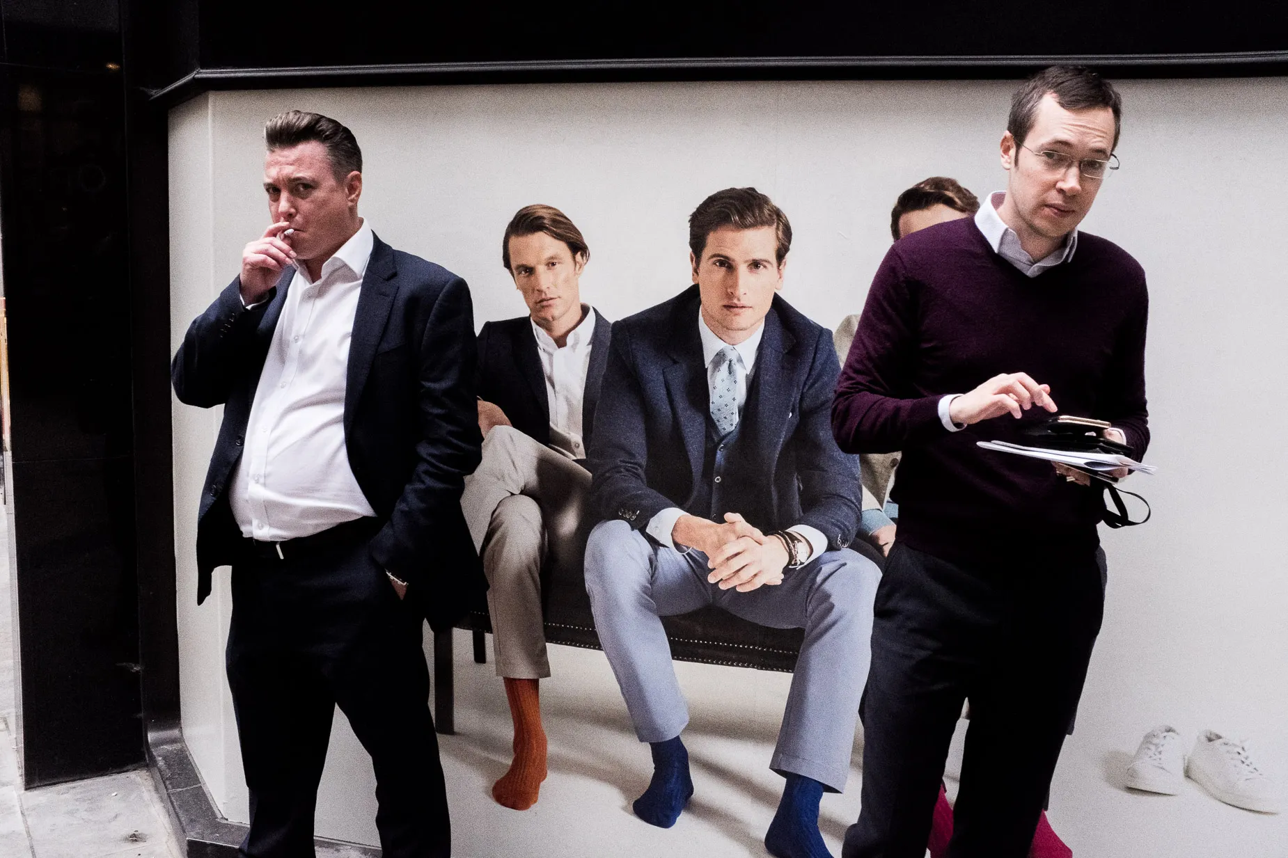 Two city men stopped in front of a billboard of well dressed city men. From the Square Mile Street photography project by Darran K Roper