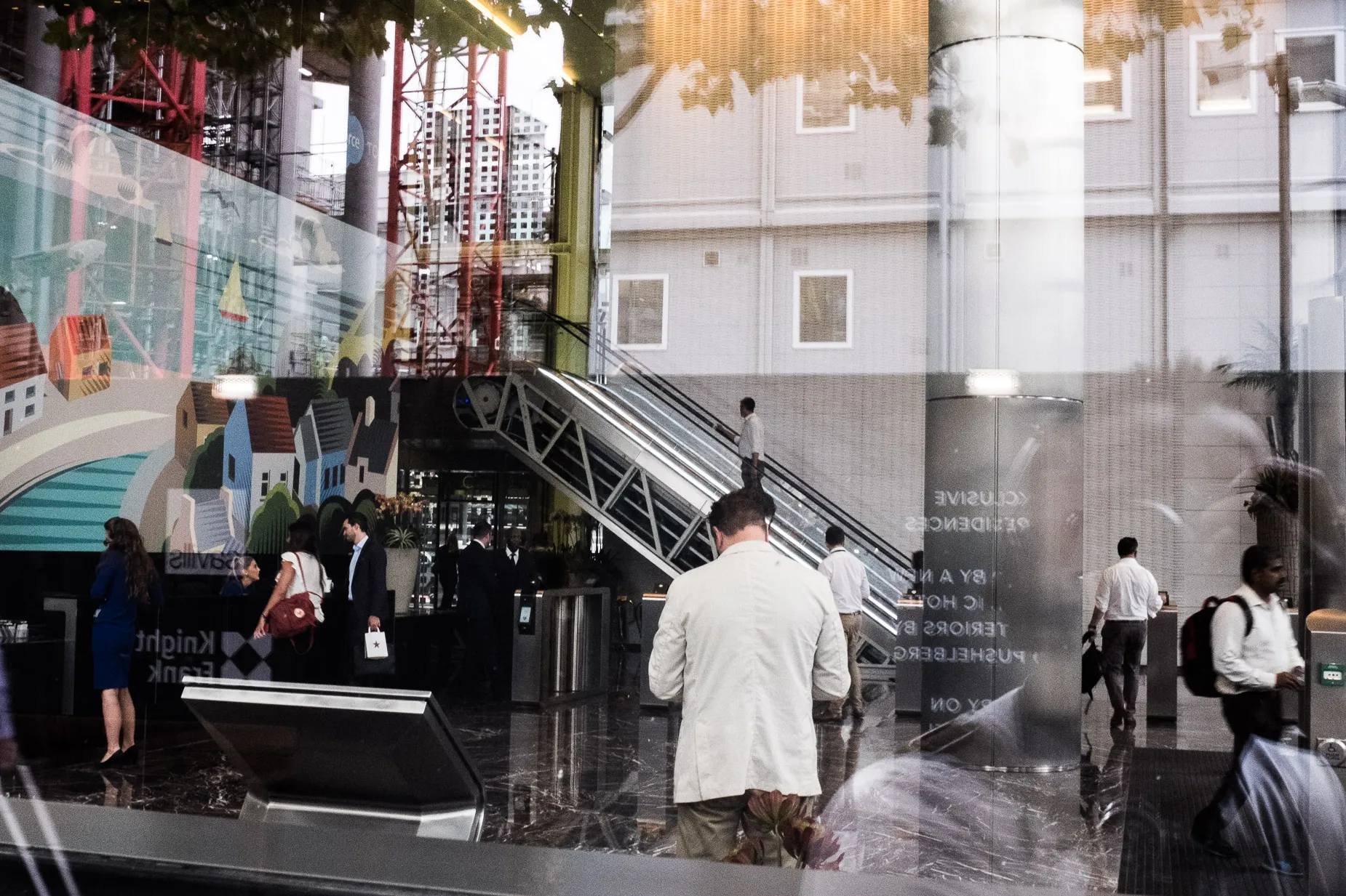 Reflection image active city people in building foyer at reception, standing walking and on escalator