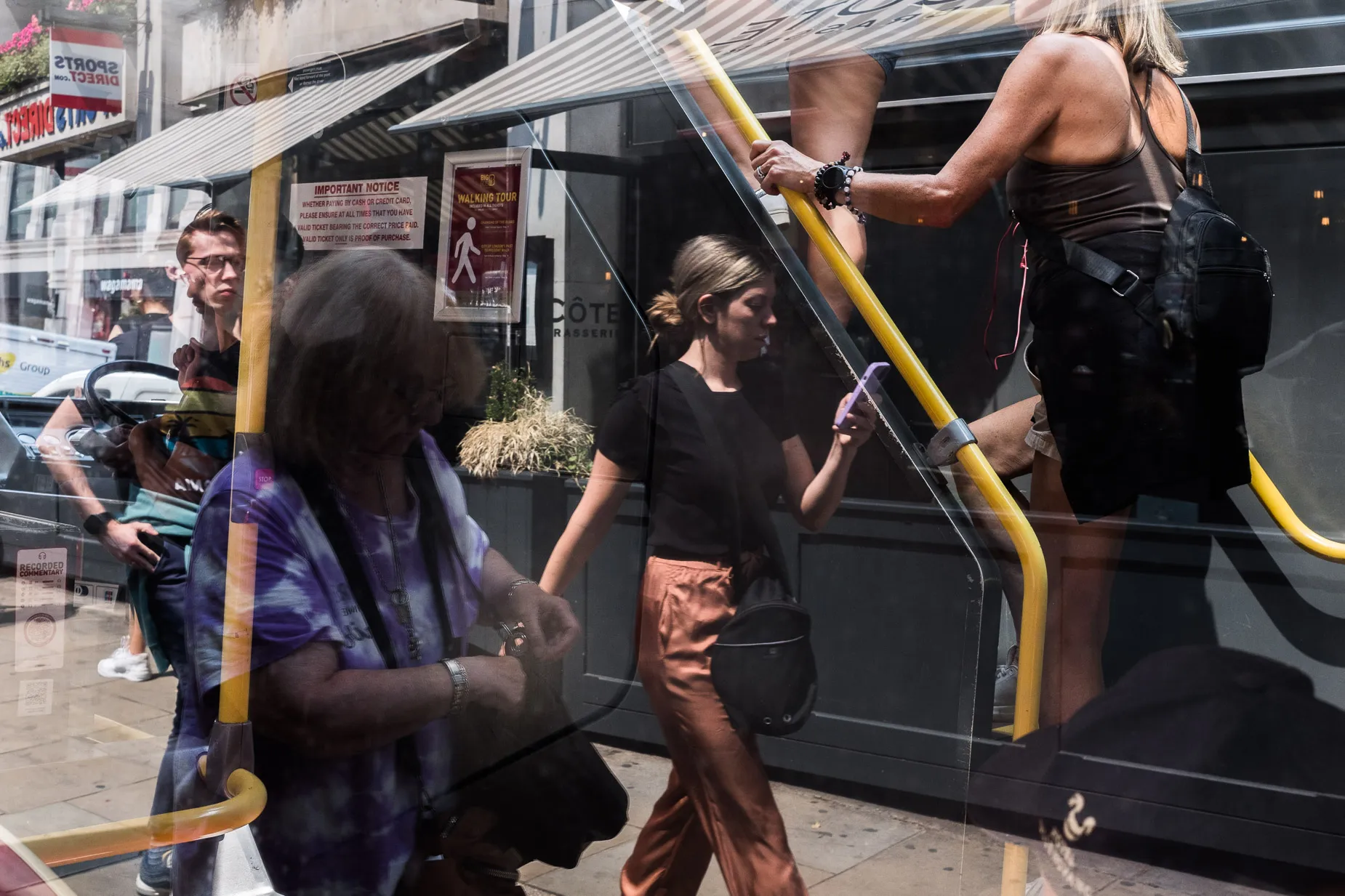 Reflections, complex layered image, pedestrians overlayed by bus occupants
