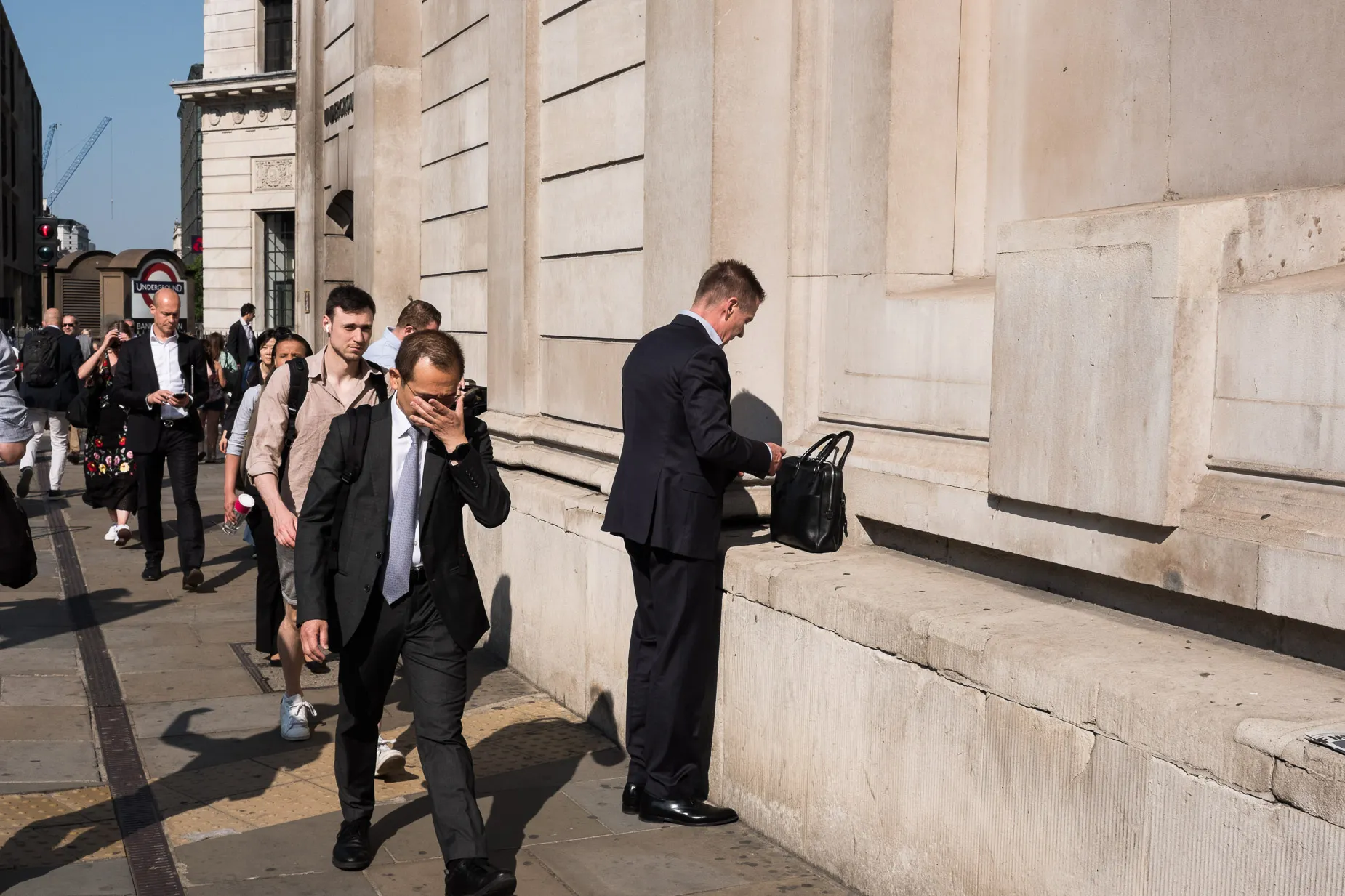 Suited man prepares himself with briefcase another suited man straightens his glasses