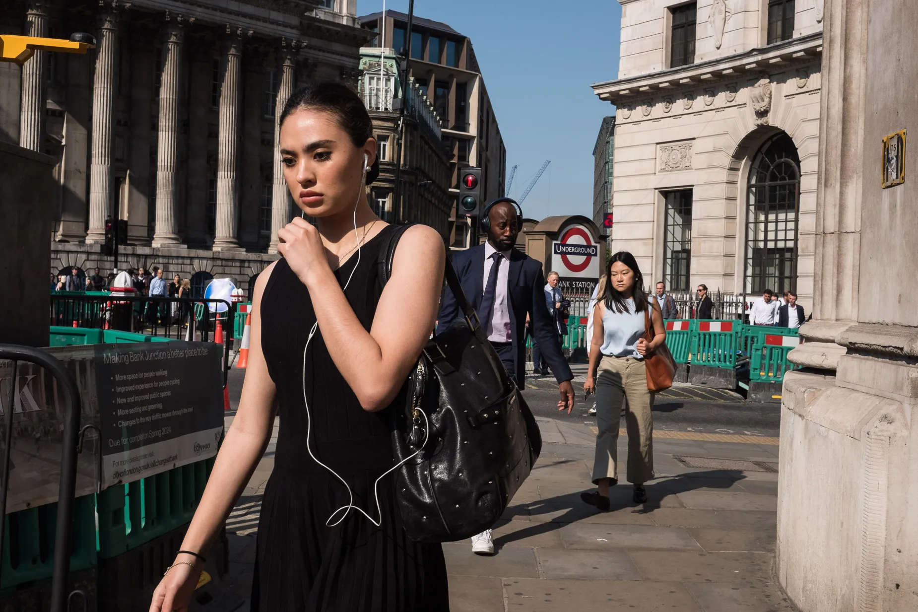Woman commuter with headphones on way to work outside the Bank of England