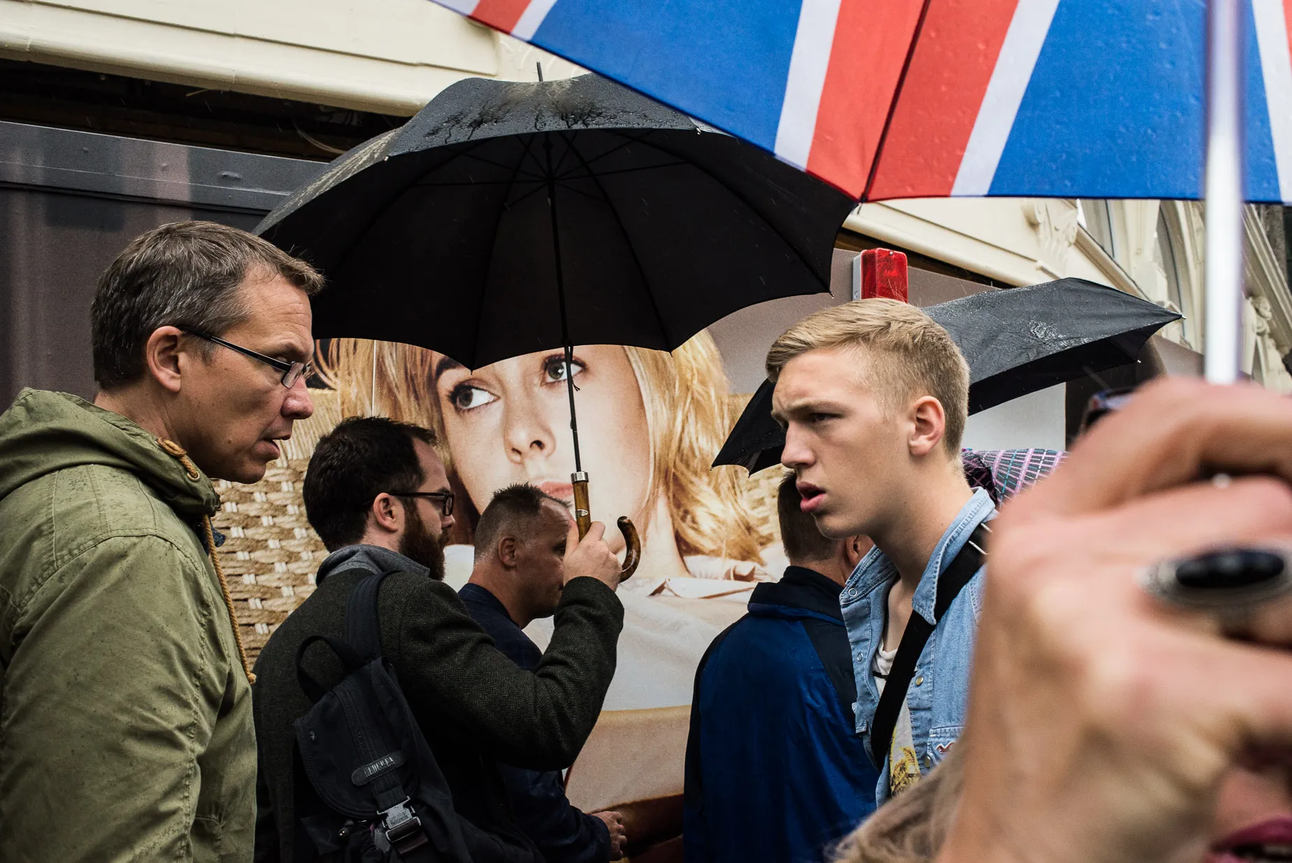 Abstract framing of umbrellas and pedestrians and billboard