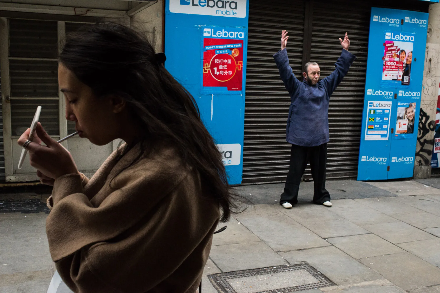 Woman attempting to light a cigarette, man performing Kungfu in the background