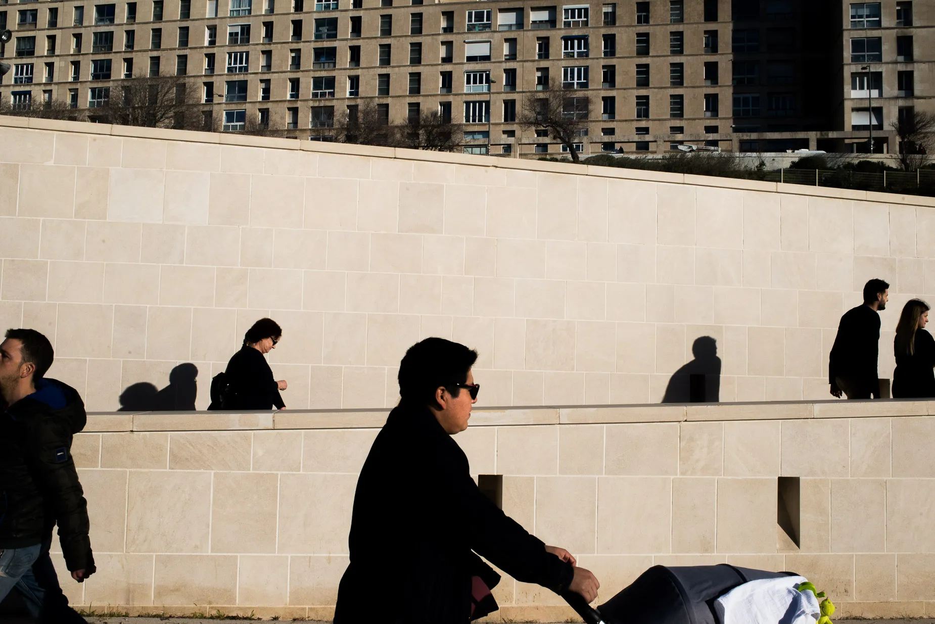 People half silhouette against layered stone walls buildings reach to the sky