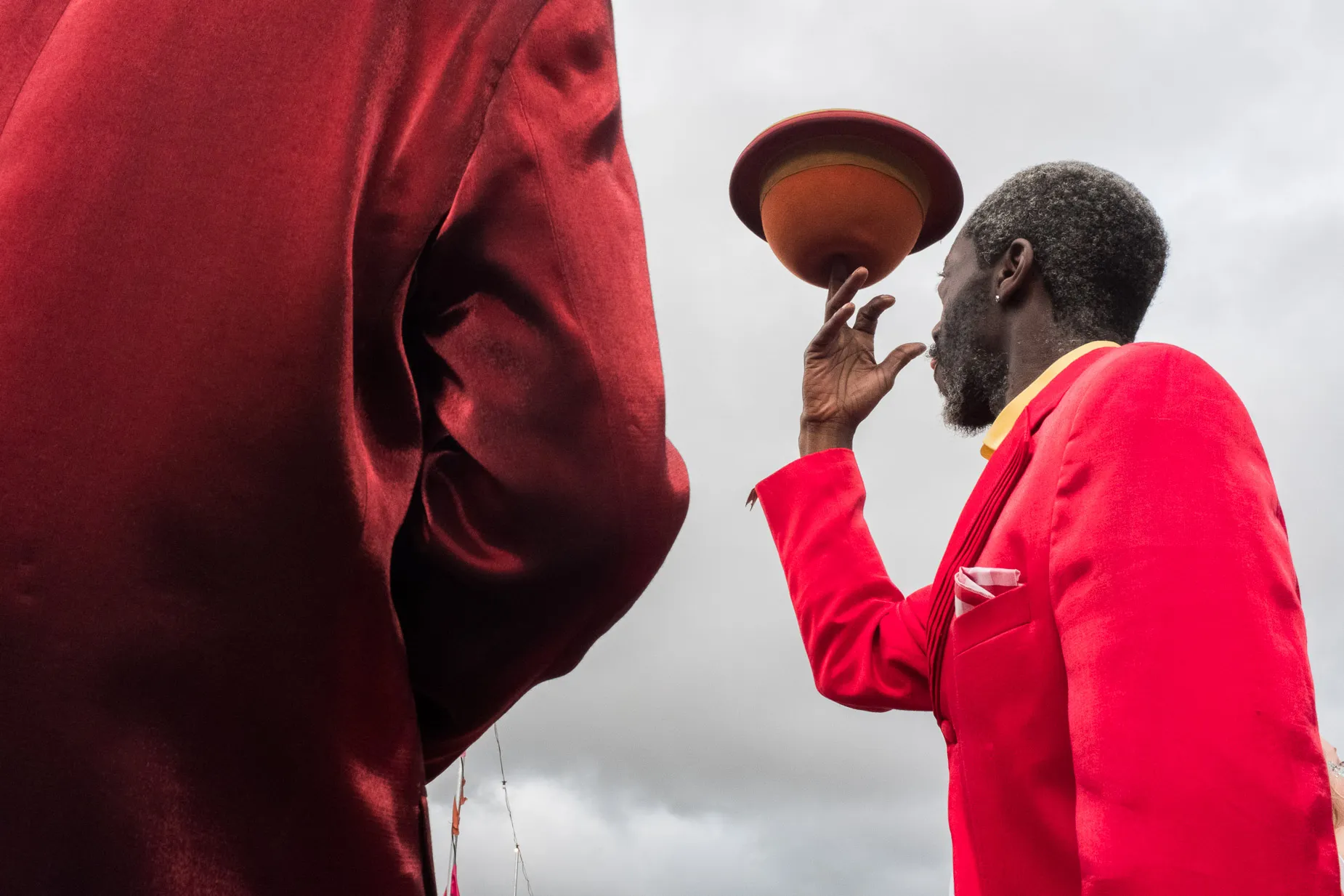 Performer in red suit balances hat on finger