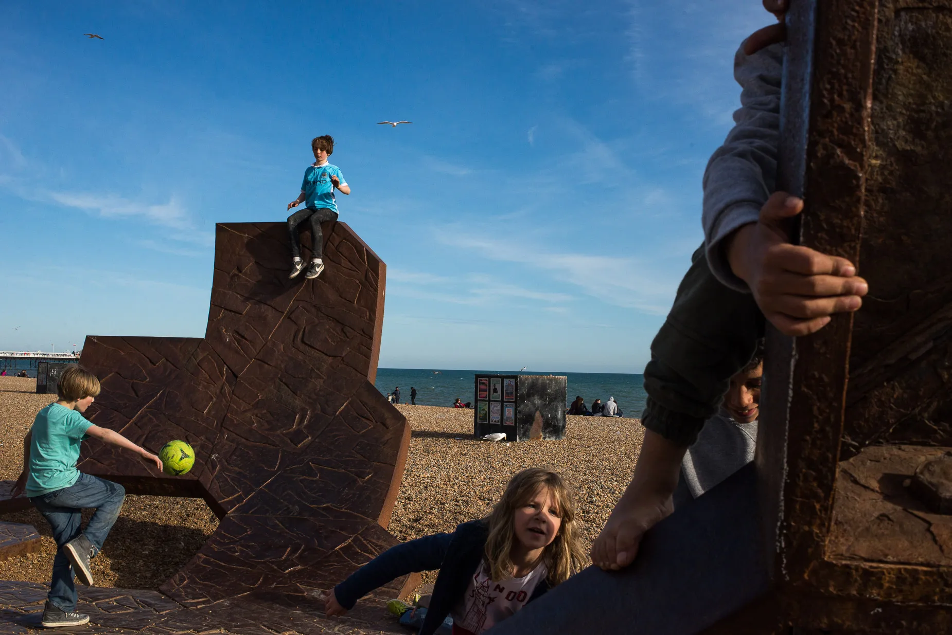 Children playing football and climbing on beach