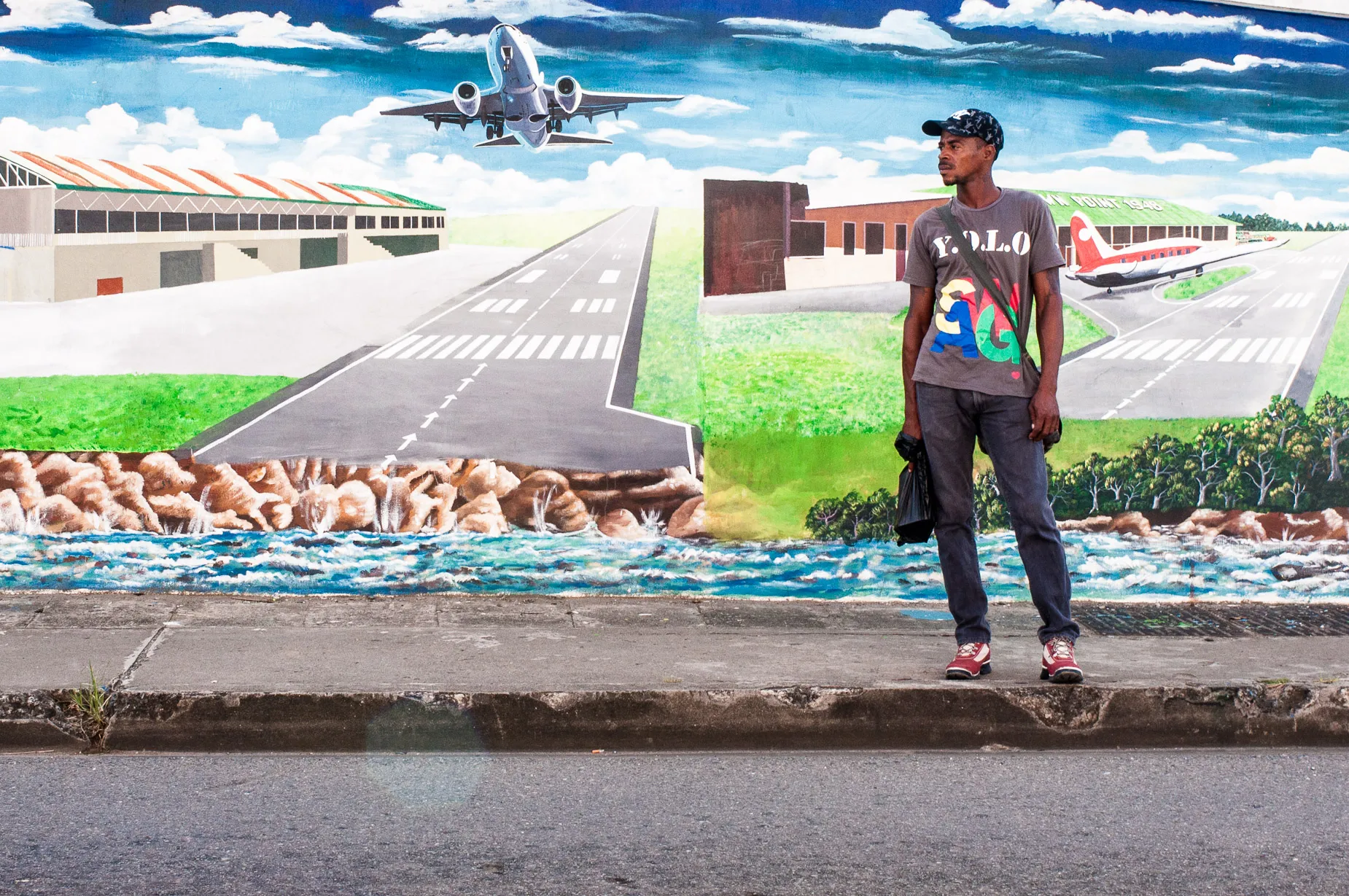 Man stands before painted mural of an airport