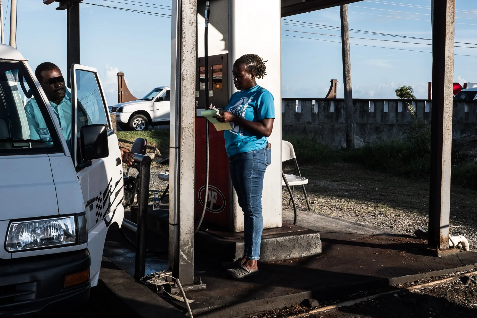 Woman service lady at gas station writes receipt in hot sun